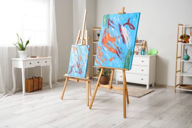 Interior of artist's workshop with paintings on easels, art supplies and commodes clipart