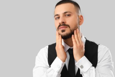 Gri arka planda yakışıklı genç sakallı adam.