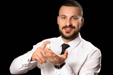 Siyah arka planda bir şişe yüz yıkama köpüğüyle yakışıklı, sakallı bir adam.