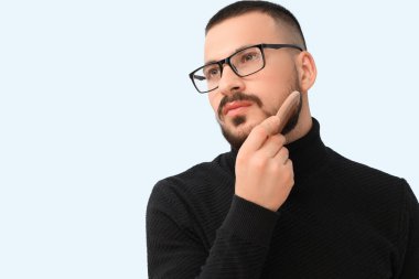 Mavi arka planda tarağı olan yakışıklı genç sakallı adam.