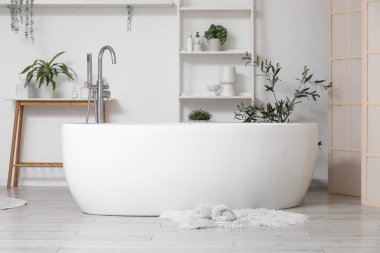 Şık banyoda, küvetin yanında, halının üzerinde yumuşak terlikler.