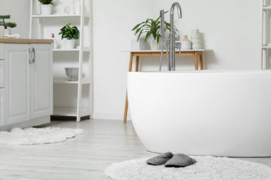 Şık banyoda, küvetin yanında yumuşak terlikli halı.