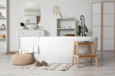 Şık banyoda, küvetin yanında, halının üzerinde yumuşak terlikler.