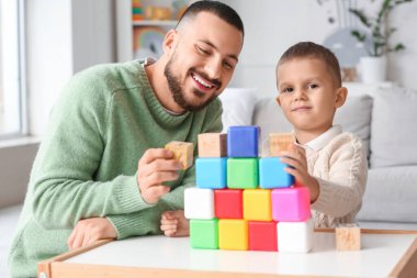 Mutlu baba ve küçük oğlu renkli küplerle dolu bir kule inşa ediyorlar.