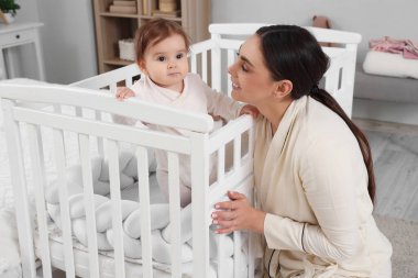 Pijamalı mutlu genç anne ve bebeği evde karyolada.