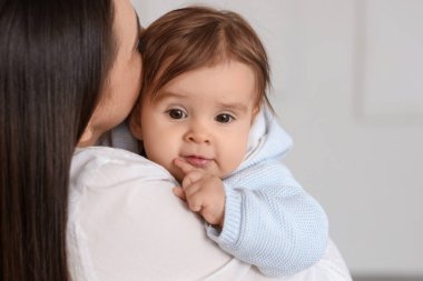 Genç anne bebeğini kucağında tutuyor, yakın plan.