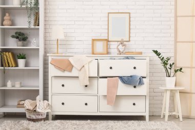 Raflarla, dağınık kıyafetlerle ve tuvaletlerle dolu dağınık bir oturma odası.