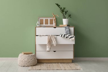 Oturma odasındaki yeşil duvarın yanında dağınık giysilerle tuvalet.