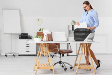 Güzel sekreter evrak çantasını ofise koyuyor.