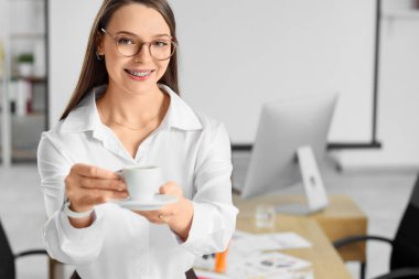 Ofisinde bir fincan kahve olan güzel bir sekreter.