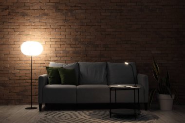 Geceleri karanlık oturma odasının içinde kanepe, masa ve parlayan lambalar.