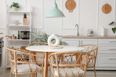 Beyaz tezgahlı, raflı ve yemek masalı açık mutfak.