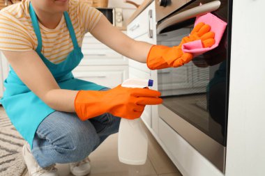 Mutfakta fırın temizleyen kadın hademe.