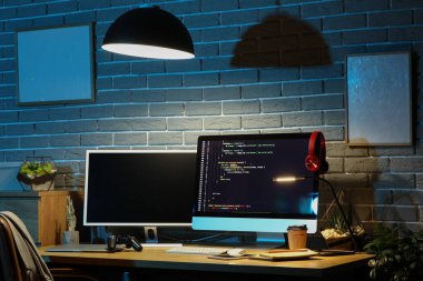 Çalışma yeri ve parlayan lambası olan karanlık programcı ofisinin içi.