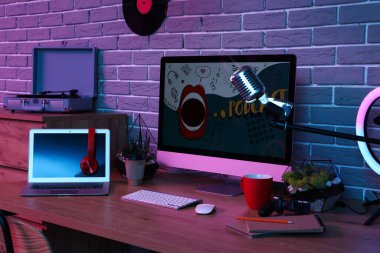 Podcaster 'ın iş yeri karanlık stüdyoda bilgisayar ve dizüstü bilgisayarla