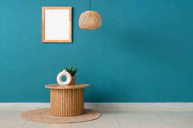 Halısı, avizesi ve koyu turkuaz duvarlı bir sehpa.