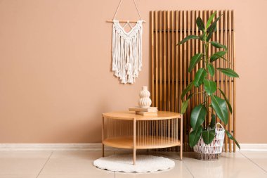 Ev bitkisi, halı ve bej duvarın yanında dekor olan şık bir kahve masası.