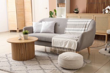 Modern oturma odasının içinde kanepe, puf ve şık kahve masası var.