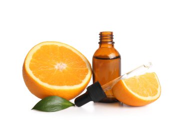 Bir şişe portakal yağı ve beyaz arka planda taze meyve.