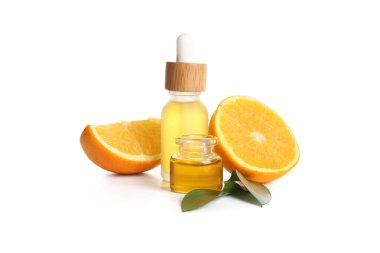 Portakal yağı şişeleri ve beyaz arka planda taze meyve.