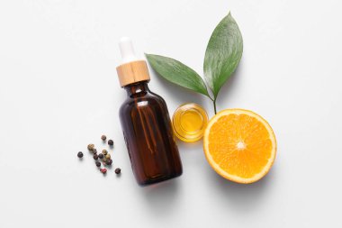 Portakal yağı şişeleri ve gri arka planda karabiber.