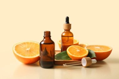 Portakal yağı şişeleri ve bej arka planda taze meyveler.