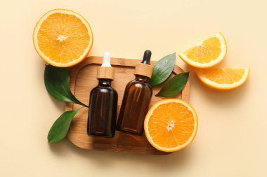 Portakal yağı şişeleri ve bej arka planda taze meyveler.