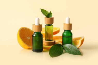 Portakal yağı şişeleri ve bej arka planda taze meyve kesimi.