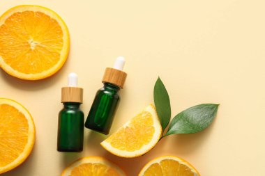 Portakal yağı şişeleri ve bej arka planda taze meyve kesimi.