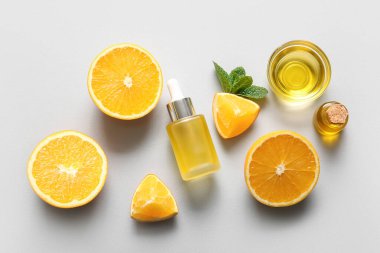 Şişeler ve cam kase portakal esaslı yağ ve gri arka planda nane.