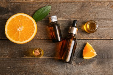 Portakal yağı şişeleri ve ahşap zemin üzerinde taze meyve.