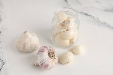 Beyaz arka planda taze sarımsak karanfilli kavanoz.