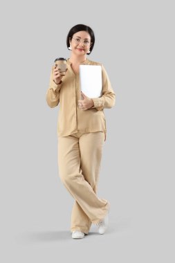 Dizüstü bilgisayarı ve arka planda kahve fincanı olan olgun bir iş kadını.