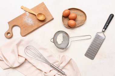 Mutfak aletleriyle kompozisyon, un ve hafif arka planda tavuk yumurtaları.