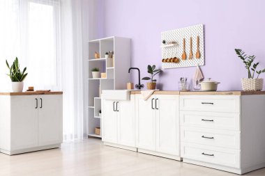 Tahtası, lavabosu ve beyaz tezgahı olan şık bir mutfak.