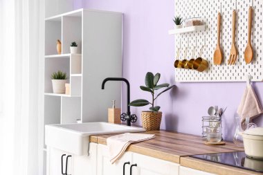 Tahtası, lavabosu ve elektrikli fırını olan şık bir mutfak.