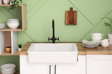 Temiz tabaklar, kase ve bardaklar şık bir mutfakta lavabonun yanında, yakın plan.