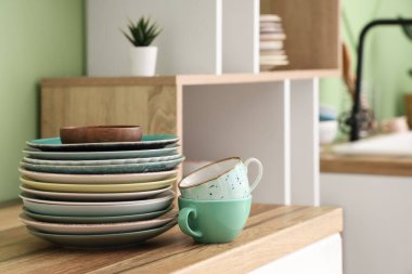 Mutfaktaki ahşap tezgahta temiz tabak ve bardaklar, yakın plan.