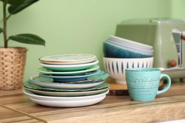 Temiz tabaklar, kaseler ve bardaklar şık mutfaktaki ahşap tezgahta, yakın plan.