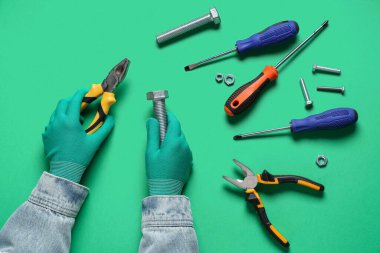 Yeşil arka planda sürgülü ve aletli tamirci elleri