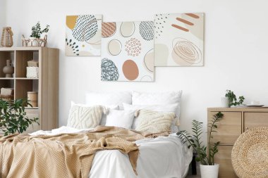Şık yatak odaları, rahat yataklar, ev bitkileri ve güzel tablolar.
