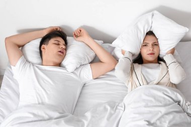 Evde kocasının gürültülü horlamasından rahatsız olan genç bir kadın.