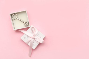 Pembe arka planda ev anahtarı olan hediye kutusu.