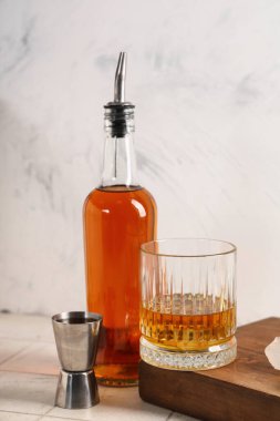 Gri arka planda bir bardak rom, şişe ve jigger. Yakın çekim.