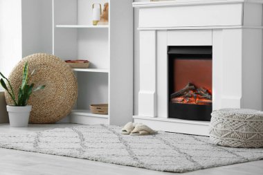 İçinde raf ünitesi, şömine ve halıda terlik olan oturma odası.