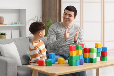 Mutlu bir baba, evdeki küplerle oğlunu alkışlıyor.