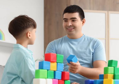 Baba ve küçük oğlu evde renkli küplerle oynuyorlar.