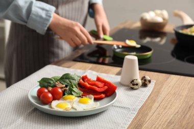 Kadın, kızarmış bıldırcın yumurtası ve taze sebze mutfağıyla lezzetli bir akşam yemeği hazırlıyor.