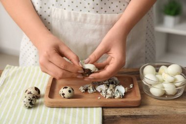 Mutfakta haşlanmış bıldırcın yumurtası soyan kadın, yakın plan.