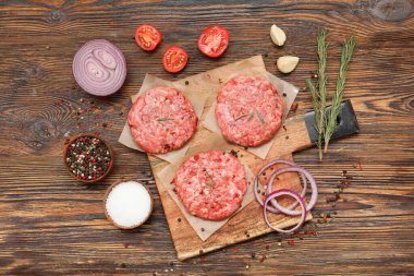 Tahtayı çiğ et ve ahşap arka planda baharatlarla kesmek.